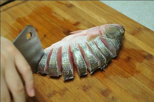 將鱸魚(yú)清洗干凈，從脊椎處切斷至腹部，腹部保留1cm左右不要切斷。