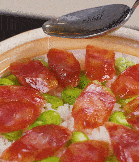 大米出現(xiàn)小孔時開蓋放香腸，往鍋邊淋入少許油，再燜煮8~10分鐘左右。