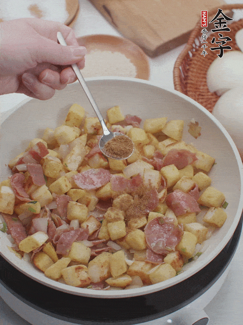 起鍋少油，煸香洋蔥丁、蔥白，加入金字培根火腿翻炒幾下，再加入饅頭丁、1小勺孜然粉、少許鹽翻炒均勻并鋪平。