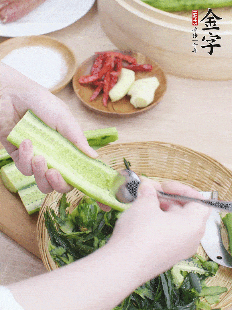 黃瓜削皮，對半切開，勺子挖去內(nèi)瓤，斜刀切片。青蒜斜刀切段。