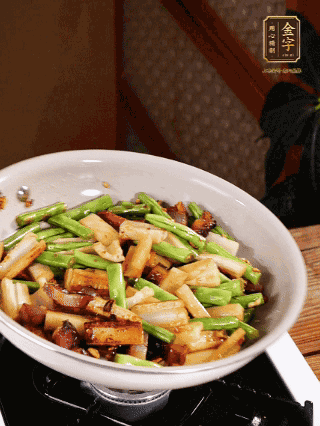 油熱下蒜末、干辣椒、醬肉煸炒出香味，依次下藕條、豆角翻炒均勻
